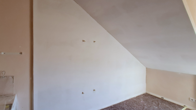 Leere Wand und Dachschräge in einem Raum vor der Installation von Flächenheizungs-Registern