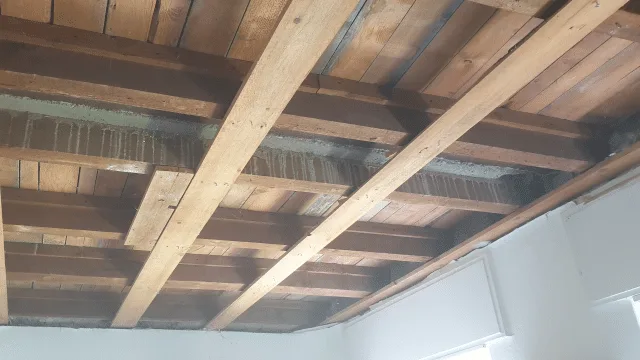Blick auf eine Decke mit sichtbaren Holzbalken und eingebauten Kunststoff-Registern