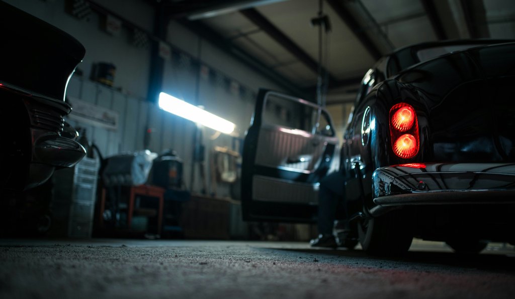 Dunkle Garage mit offenem Autotür und rotem Rücklicht eines Fahrzeugs