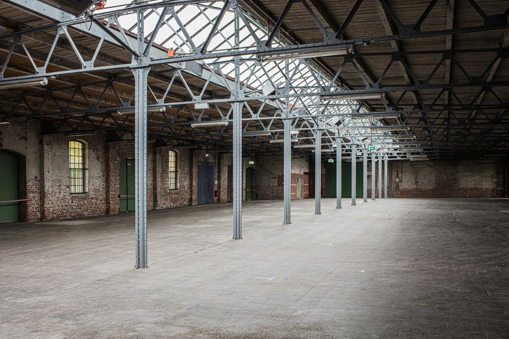 Große leere Industriehalle mit Stahlträgern und Backsteinwänden