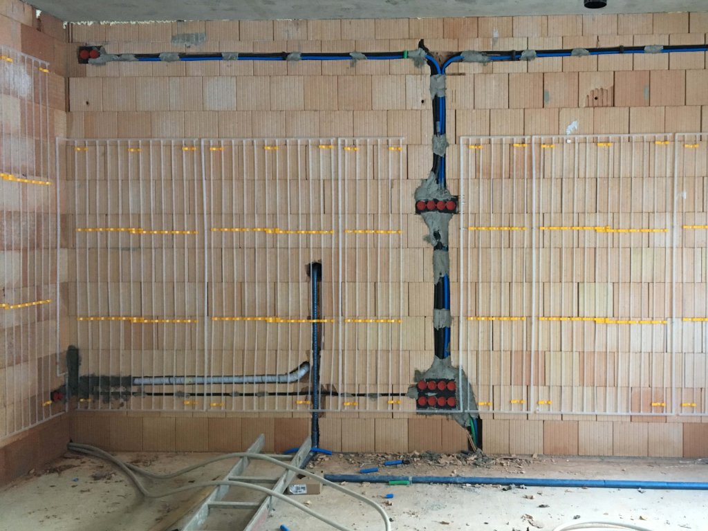 Innenraum mit freiliegenden Leitungen und Rohren an einer Wand aus Ziegelsteinen
