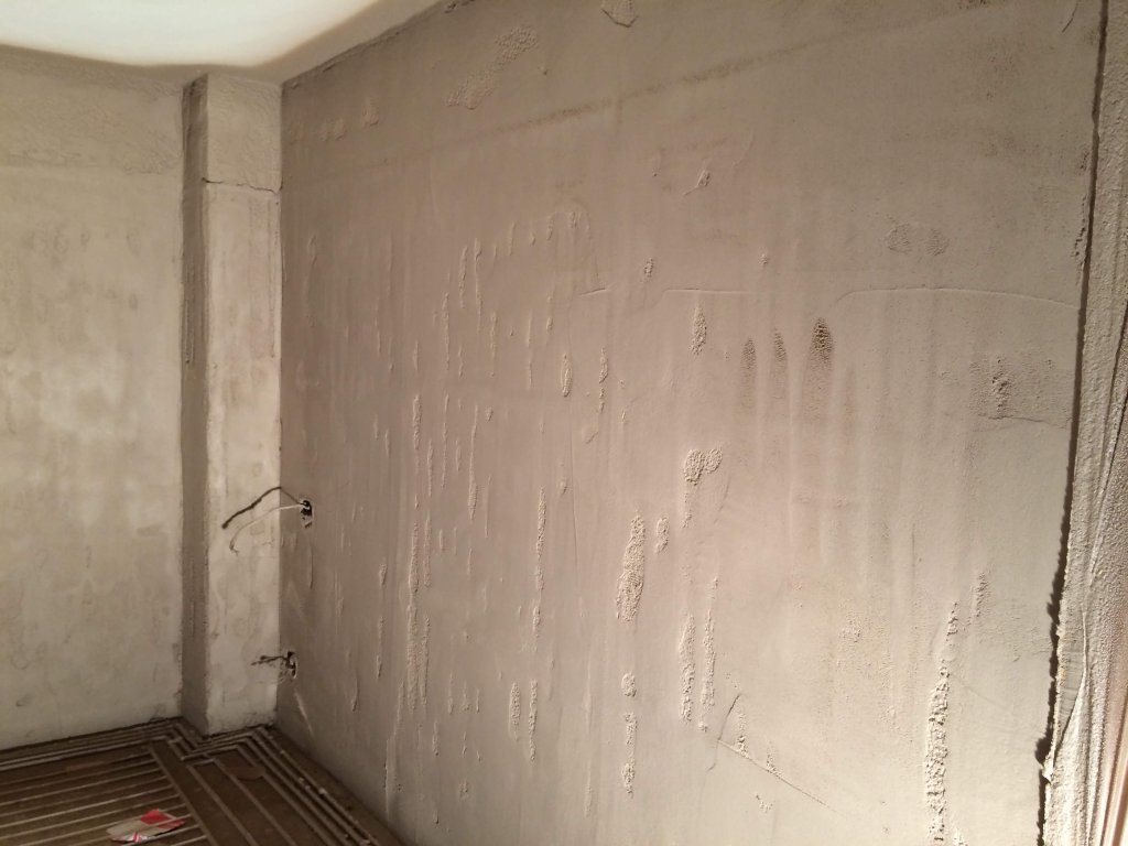 Rohbauwand mit Heizungsrohren und unvollständigem Estrichboden