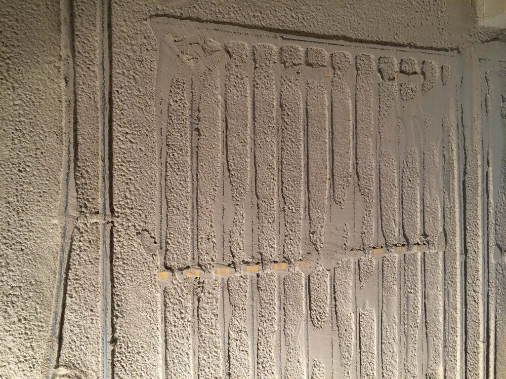 Nahaufnahme einer Wand mit aufgetragenem Putz und sichtbaren Rillen