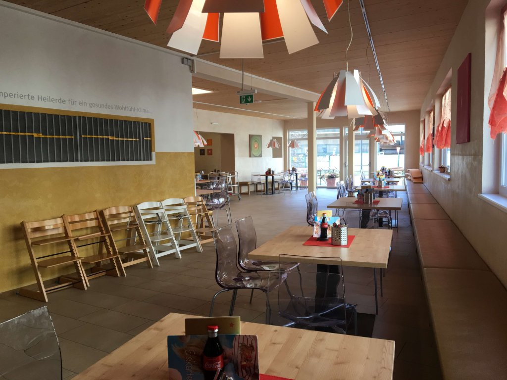 Innenraum eines hellen Restaurants mit Tischen, Stühlen und moderner Beleuchtung