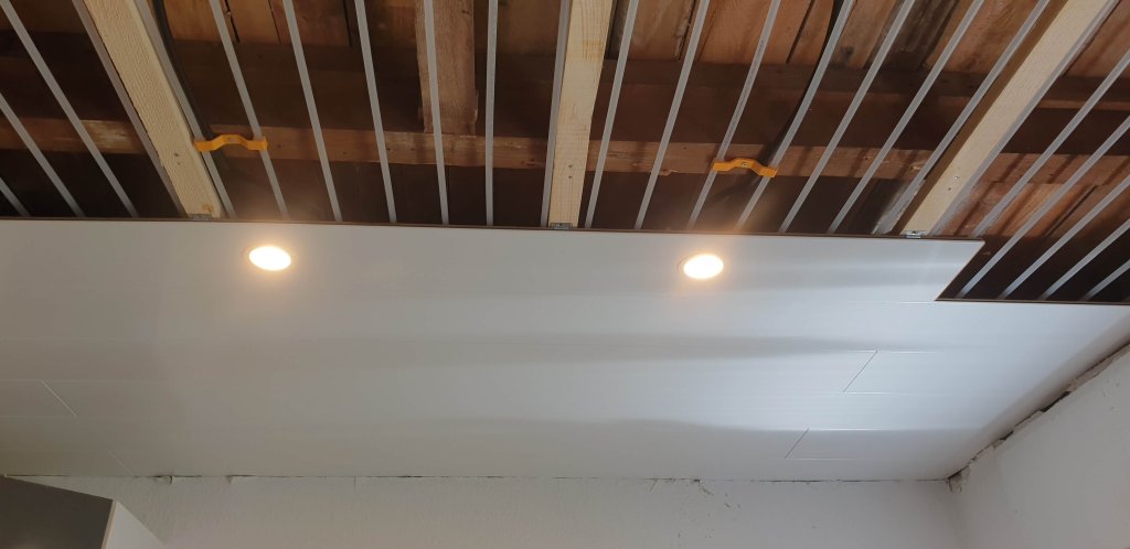 Decke mit sichtbaren Rohrleitungen und eingebauten Deckenleuchten