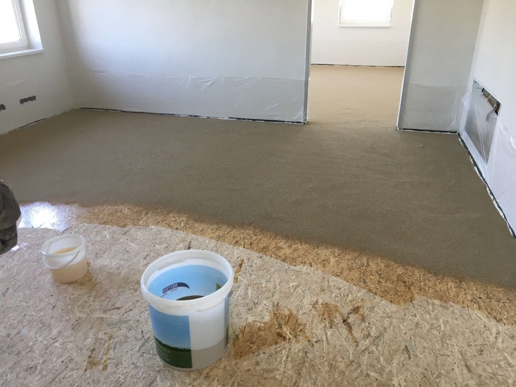 Boden mit frischem Estrich in einem hellen Raum mit Eimern im Vordergrund