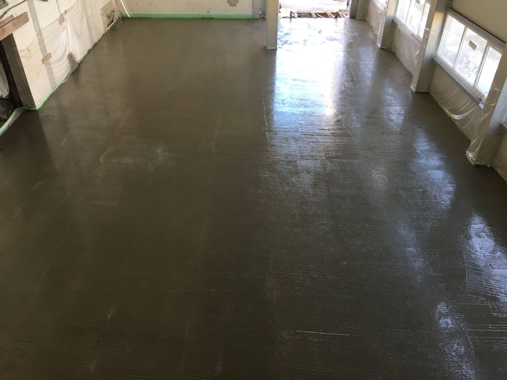 Großer Raum mit frisch gegossenem glattem Betonboden und Fenstern an den Wänden