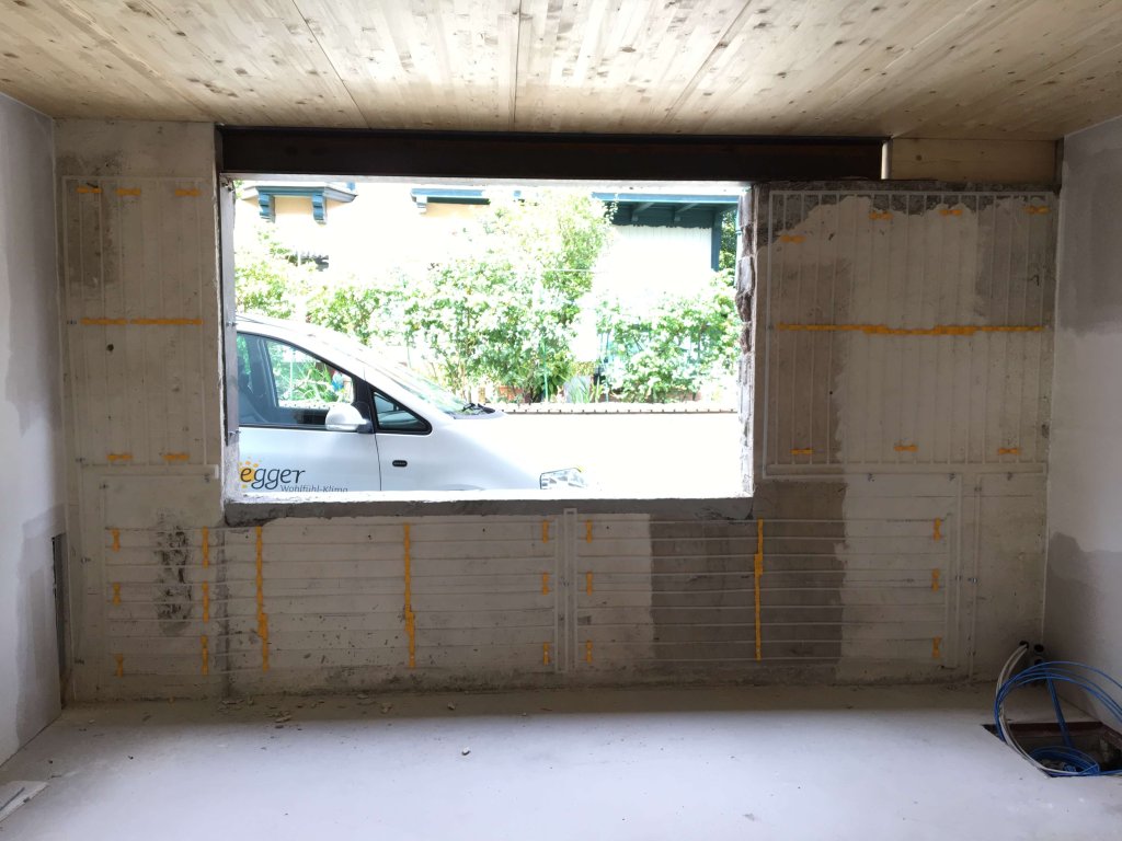 Rohbau mit großem rechteckigem Fenster und Blick auf weißen Van draußen