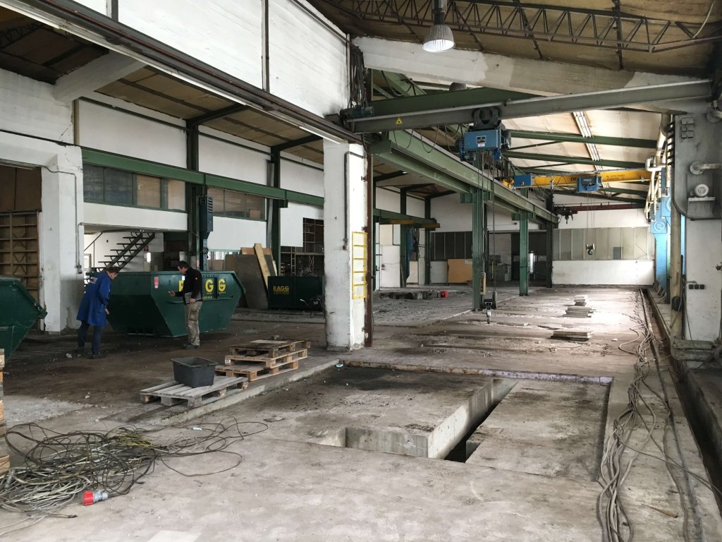 Leere Industriehalle mit Betonboden und Kabeln auf dem Boden