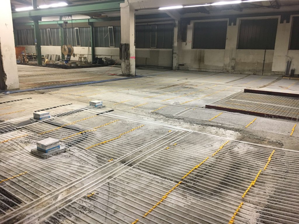 Große Halle mit sichtbaren Rohrleitungen und Installationen auf dem Boden