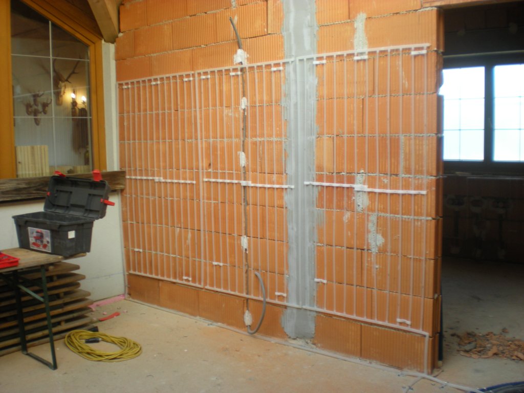 Rohbauwand mit installierten Heizungsrohren und offenem Fenster im Raum