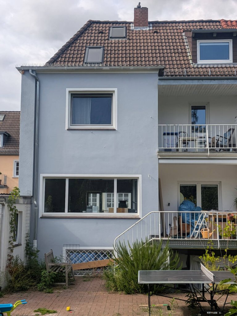 Mehrfamilienhaus mit Balkon und Garten im Vordergrund
