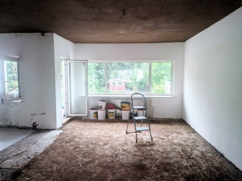 Leerer Raum mit offenem Fenster, Leiter und Baumaterialien auf dem Boden