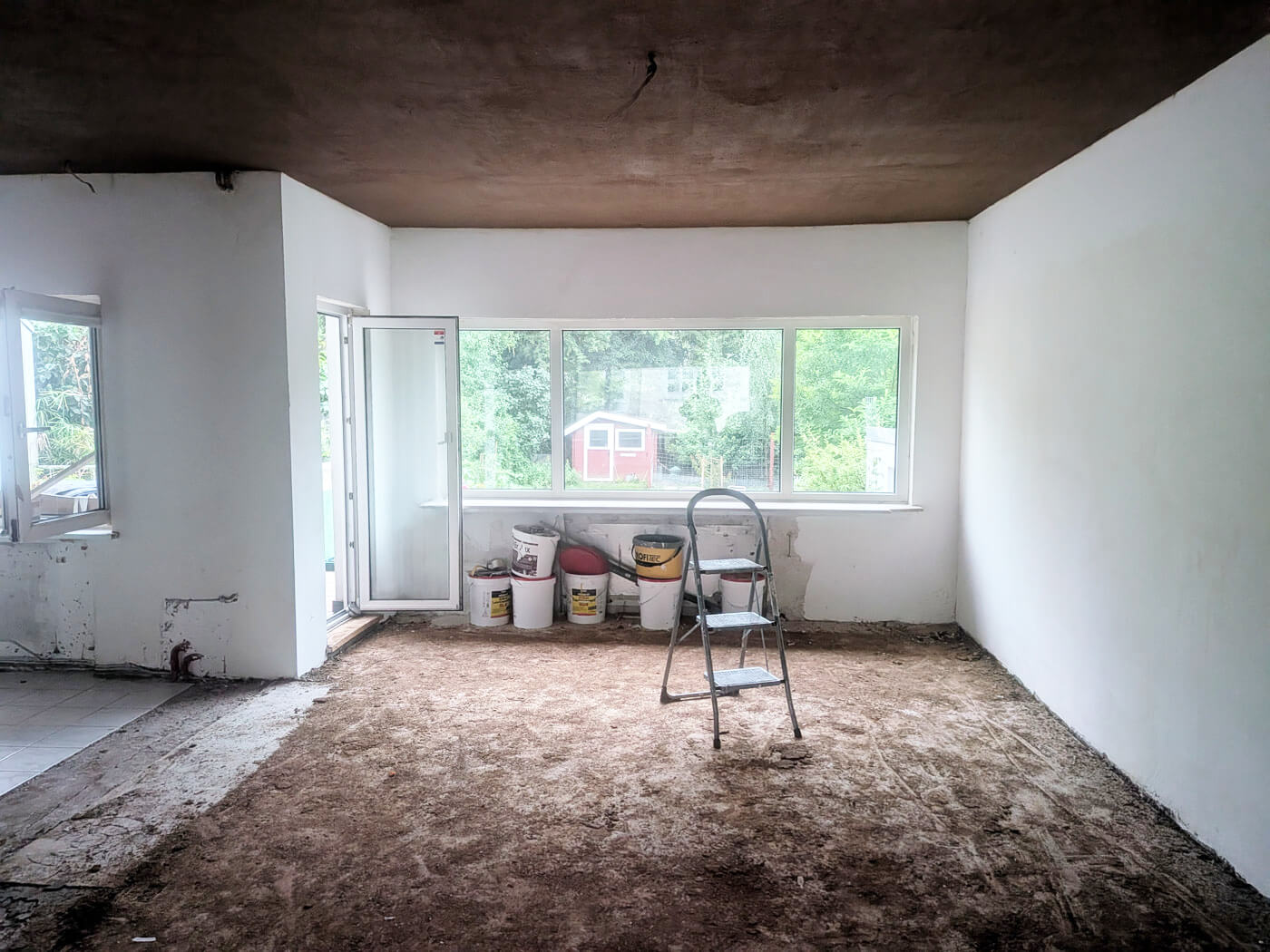 Leerer Raum mit offenem Fenster, Leiter und Baumaterialien auf dem Boden
